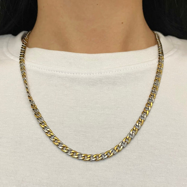 Gold chain necklace worn by a person on a white background