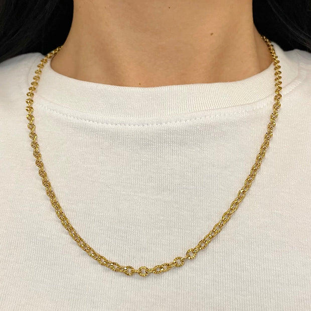 Gold chain necklace worn by a person on a white background